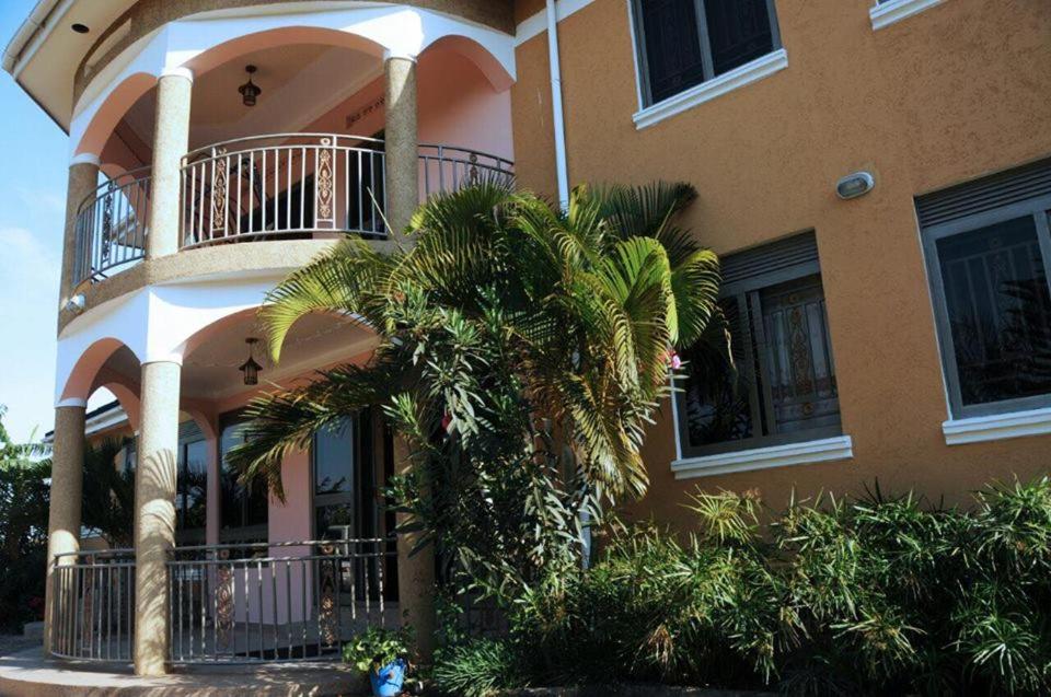 un bâtiment avec un palmier en face dans l'établissement Palace Hotel, à Mbarara