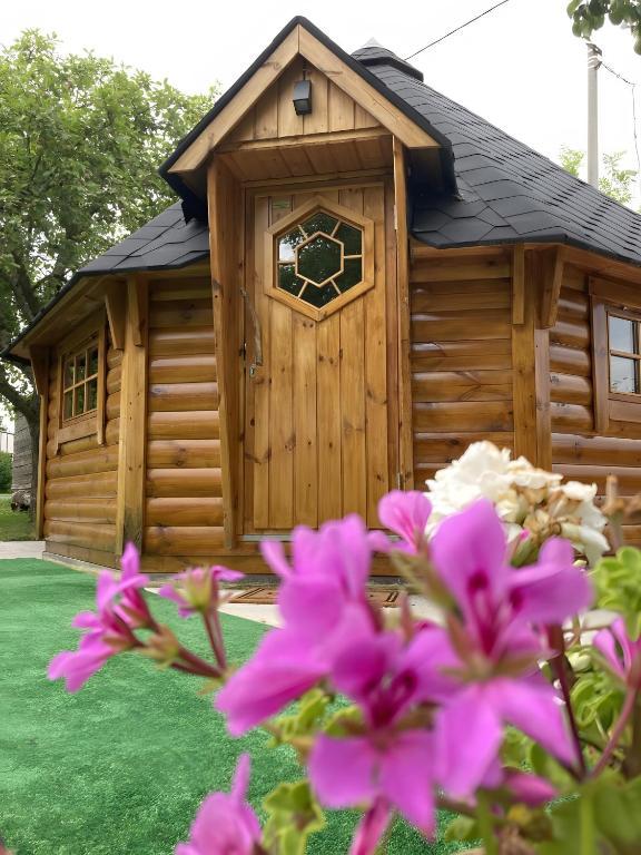 a wooden cabin with a window and pink flowers at Le Kota Du Paradou in Givet
