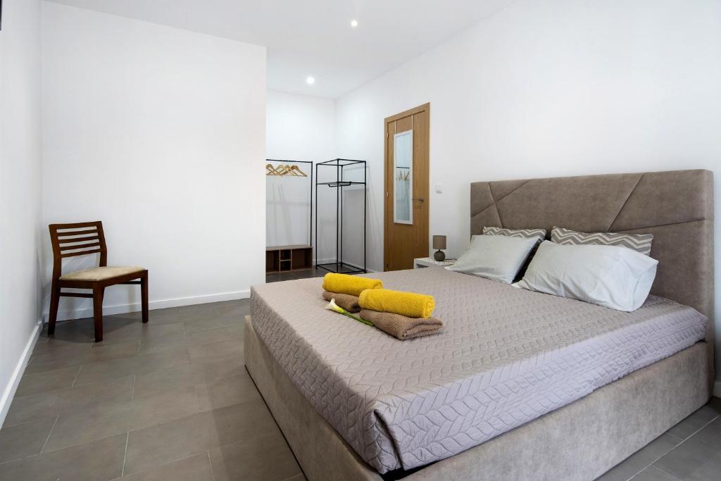 a bedroom with a large bed and a chair at Capelas Pdl Apartment in Capelas