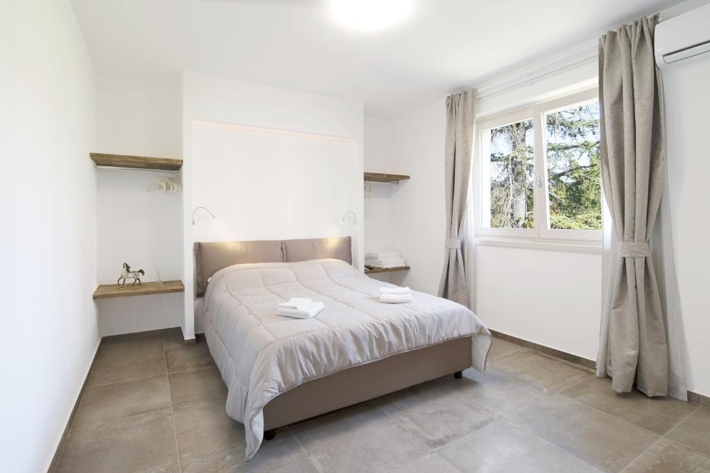a white bedroom with a bed and a window at Appartamenti Dama 1 in Bardolino
