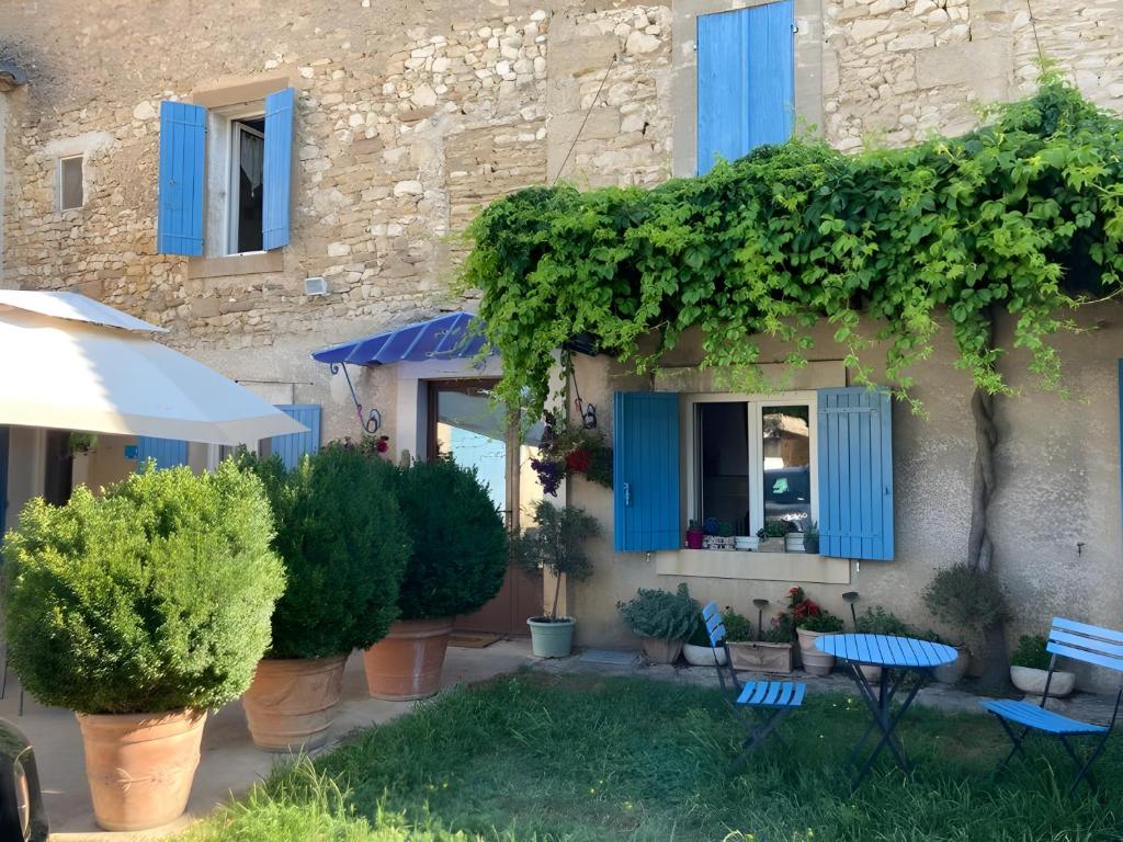 a building with blue shutters and plants on it at Mas de Maussan in Robion en Luberon