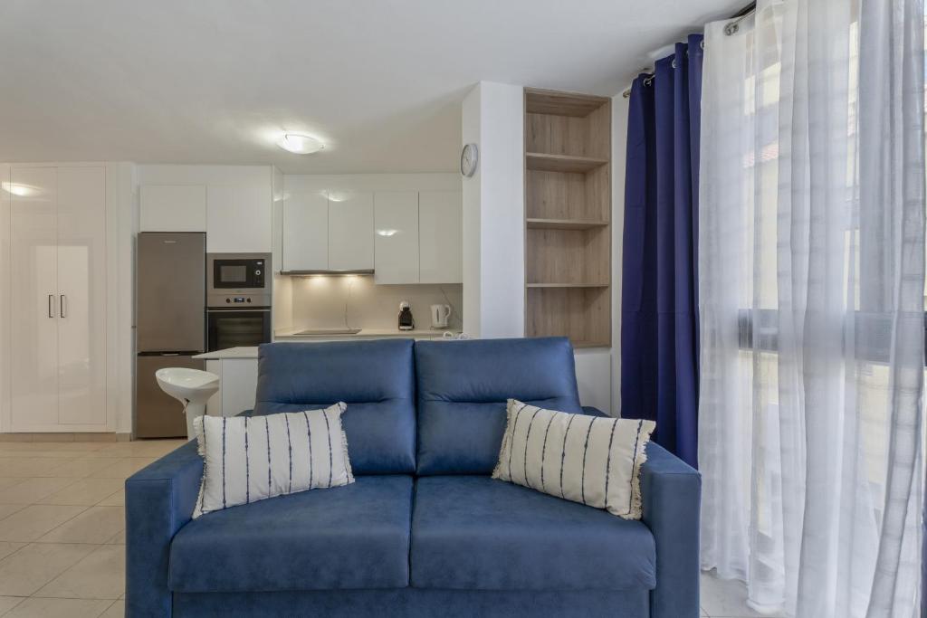 a blue couch in a living room with a kitchen at Apartamento Estrella in Candelaria
