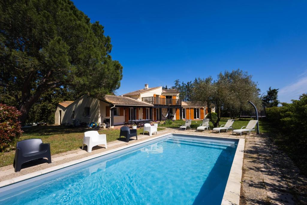 a swimming pool with chairs and a house at Bastide des vignes, piscine privée in Trèbes