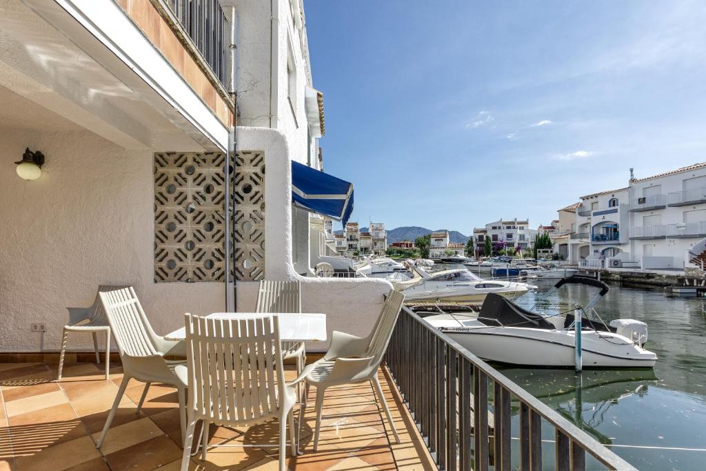 a balcony with chairs and a table and a boat at Port Empúries in Empuriabrava