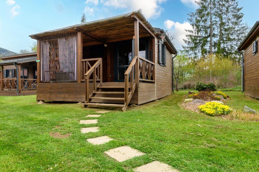 a log cabin with a porch and a grass yard at Chalet Spa 2 Terrasse des Bouleaux in Ranspach