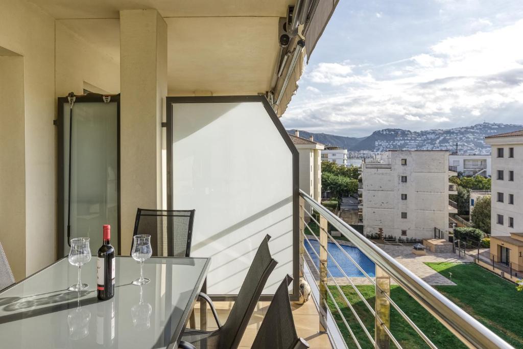 a balcony with a glass table and wine glasses at Roses Apartaments Luxury Duplex in Roses