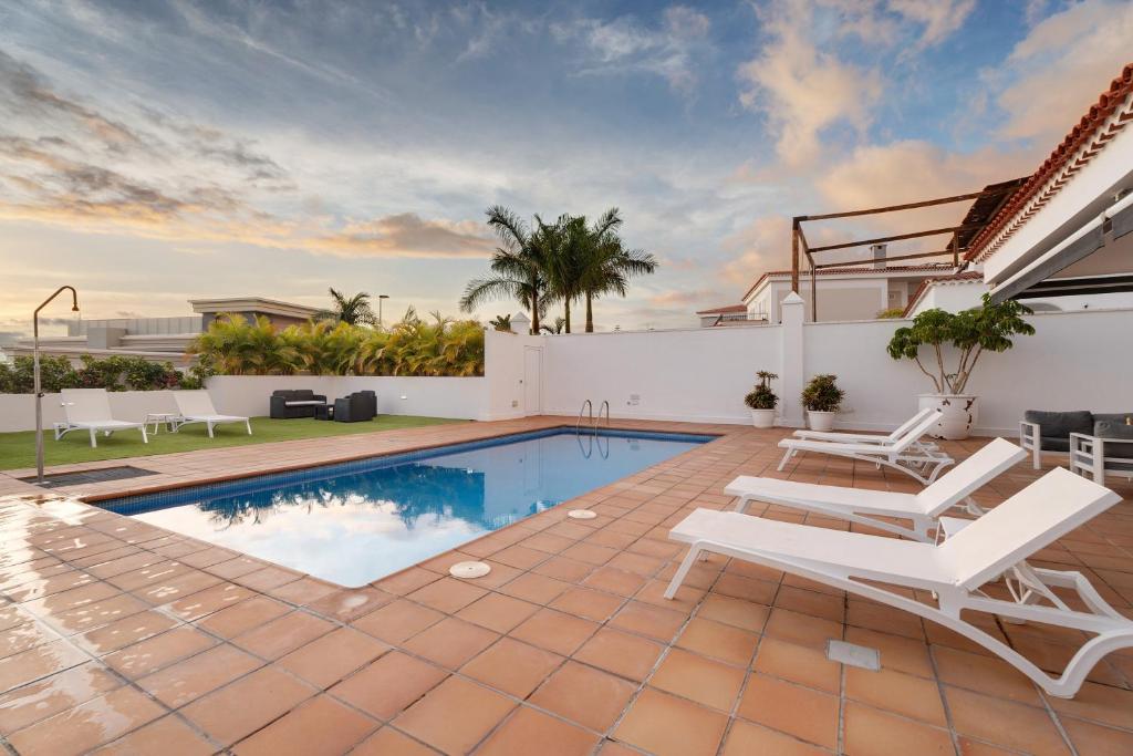 a villa with a swimming pool and patio furniture at Villa Aurora Playa La Arena in Puerto de Santiago