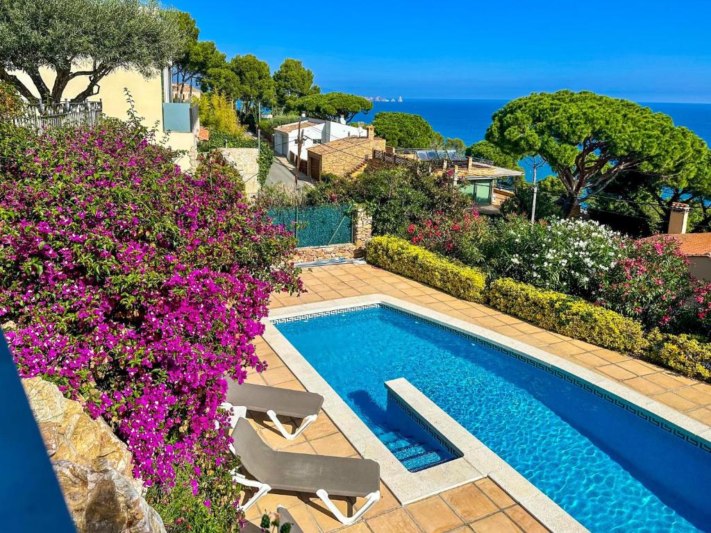 a swimming pool surrounded by flowers and the ocean at Roc Blau in Begur