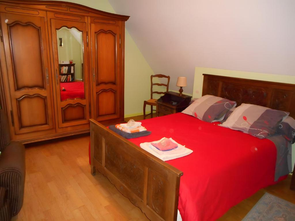 a bedroom with a red bed and a wooden cabinet at Chambre De Convenant Hery Bihan in Coatreven