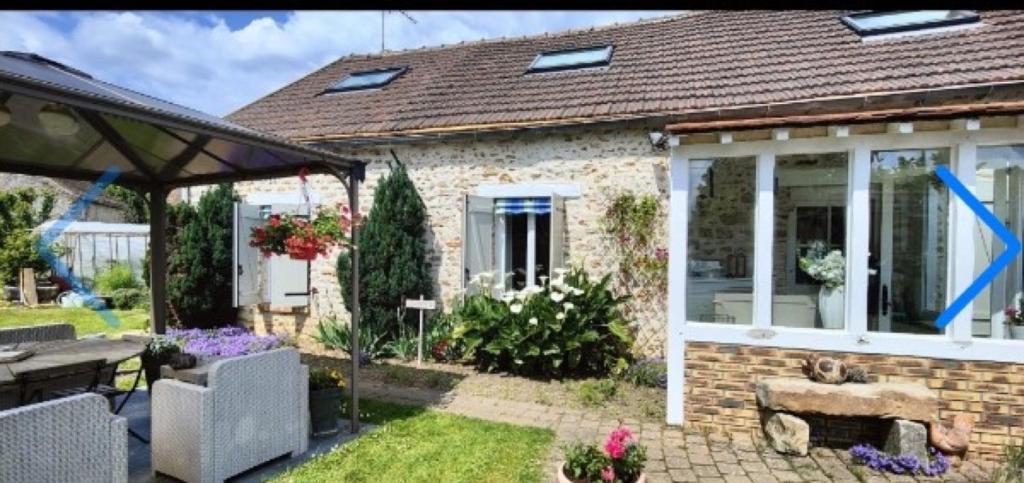 a brick house with a conservatory with a blue arrow at Les Chambres De Martine Et Guy - in Sermaise