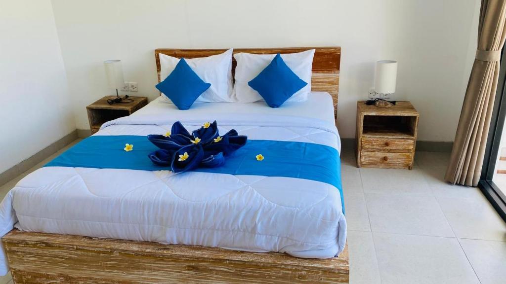 a bedroom with a large bed with blue pillows at Evara Hill Homestay in Uluwatu