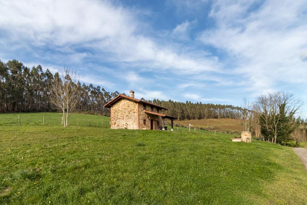 an old stone building on a grassy field at Casa Alba in Bárcena de Cicero