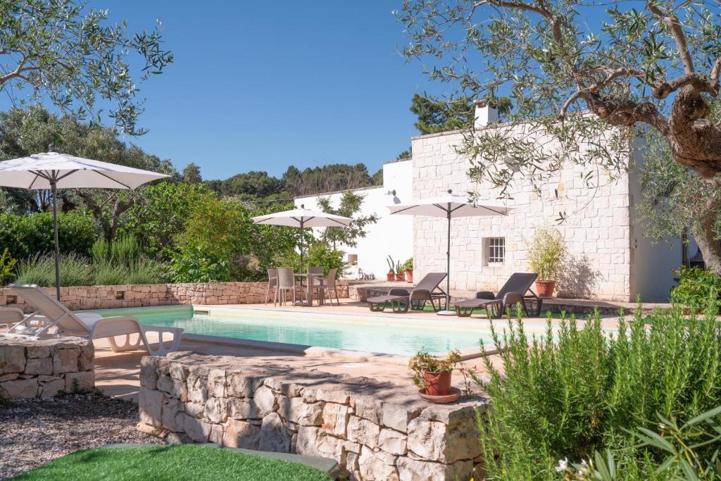 a pool with chairs and umbrellas next to a house at Villa Trullo Vecchia Aia in Alberobello