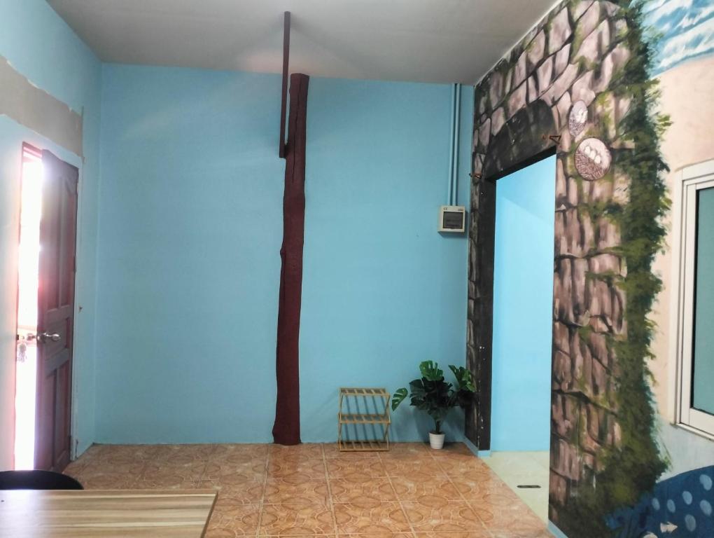 a room with blue walls and a stone wall at Happy house in Ban Khlong Son