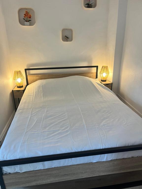 a bedroom with a white bed with two lights on it at Bleu Mandarou in Millau