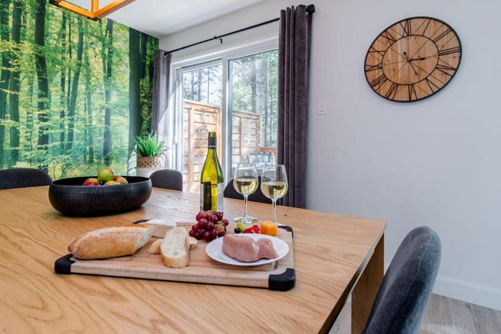 a wooden table with a plate of food and wine glasses at Le Taiga - Pool Table Nature Pet Friendly in Pont-Rouge
