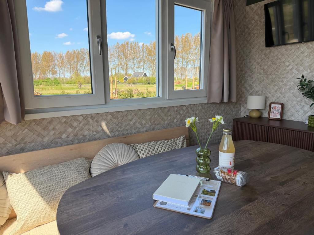 a table with a book on it with windows at De Ree Tiny House Tussen de Dijken in Driewegen