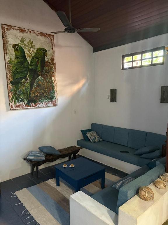 a living room with a blue couch and a painting on the wall at Refúgio da Vila in Ilhabela