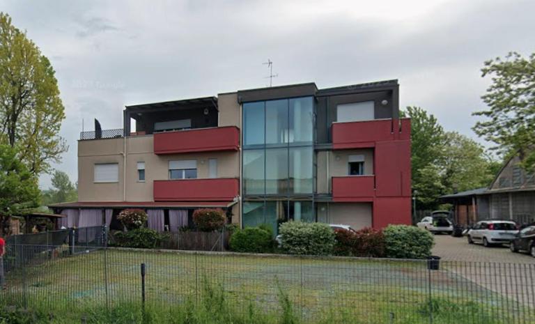 a building with red and glass windows next to a parking lot at Casa SanZvan - Appartamento in San Giovanni in Persiceto