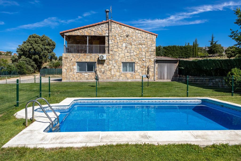 a villa with a pool in front of a house at La Nave de Gredos in Burgohondo