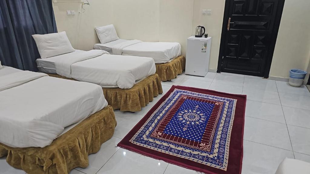 a room with three beds and a rug on the floor at عمارة دار الضيافة in Medina