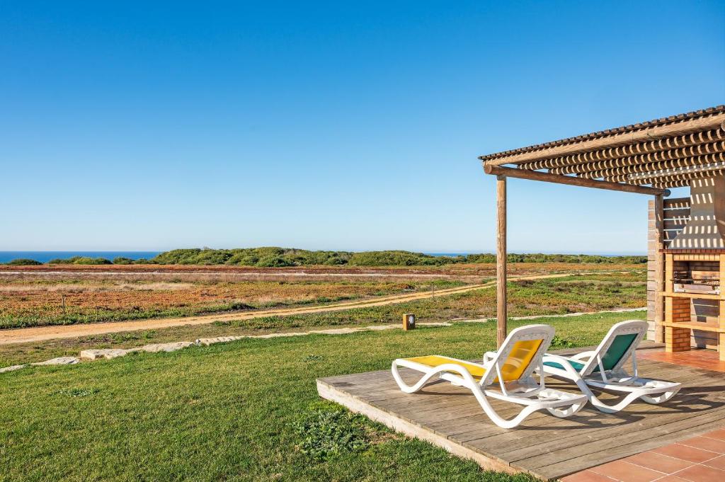 two chairs sitting on a deck near a field at Paraiso da Serva - Courela da Serva in Odemira