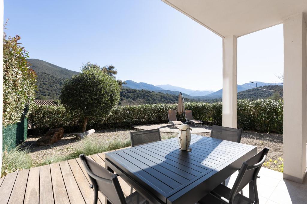 a blue table and chairs on a patio with mountains in the background at Residence Cismonte in Morosaglia