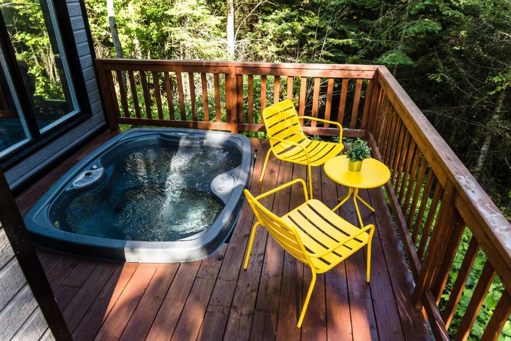 a deck with a hot tub and two chairs and a table at Chalet Victoria - Private Spa & Nature in Pont-Rouge