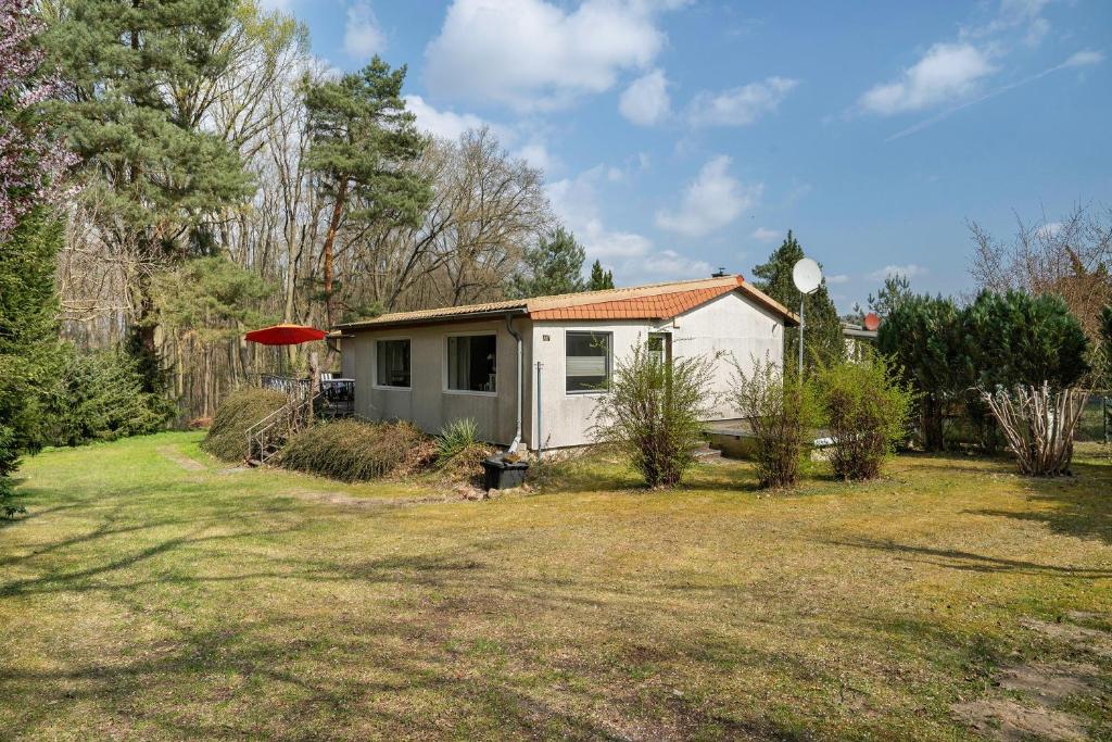 a small white house in a yard at Baumfuchs Ferienbungalow in Wesenberg
