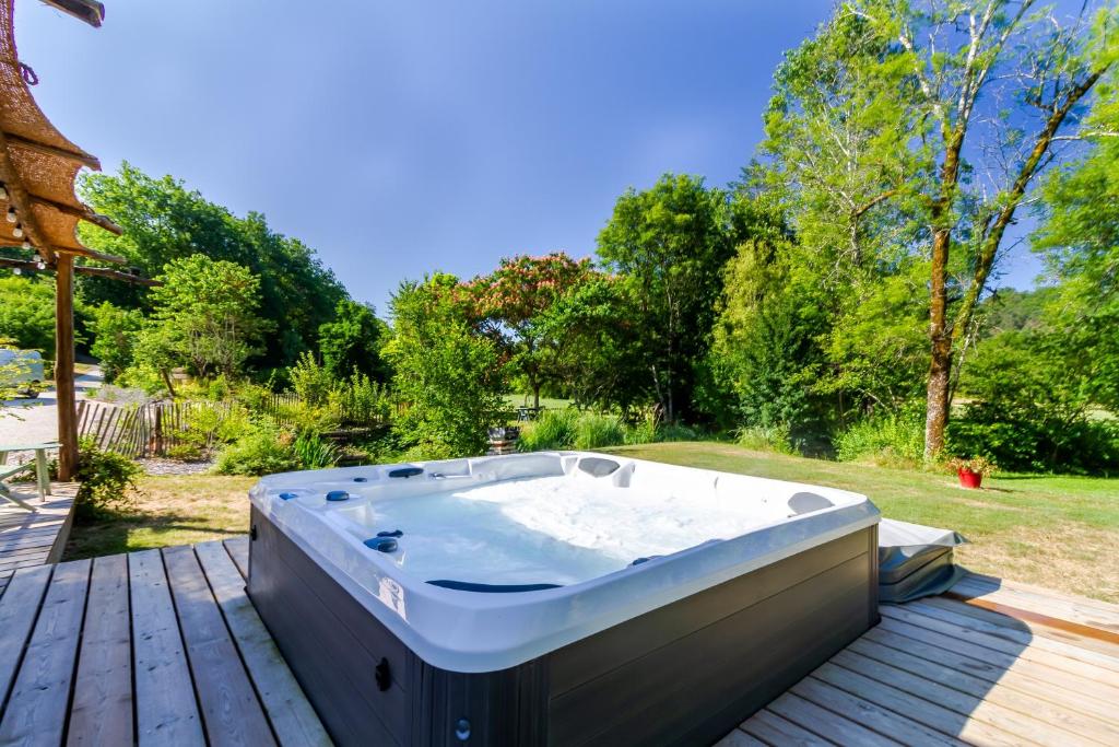 a hot tub sitting on a wooden deck at Moulin au coeur de la nature in Thonac