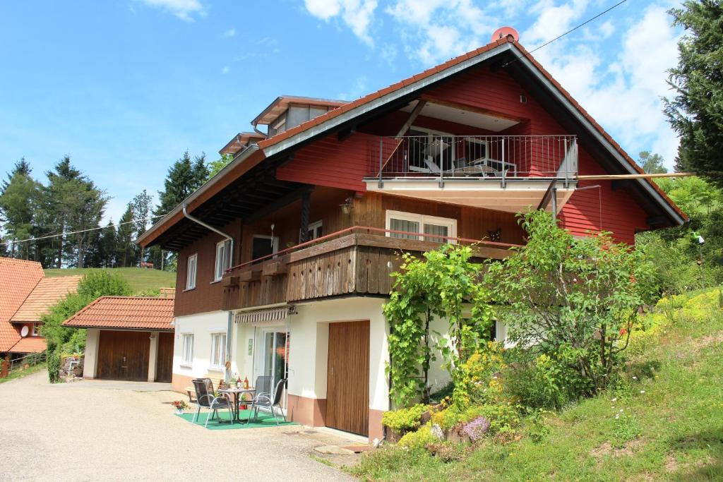 a red house with a balcony on top of it at Ferienwohnung Berghansenhof in Wolfach