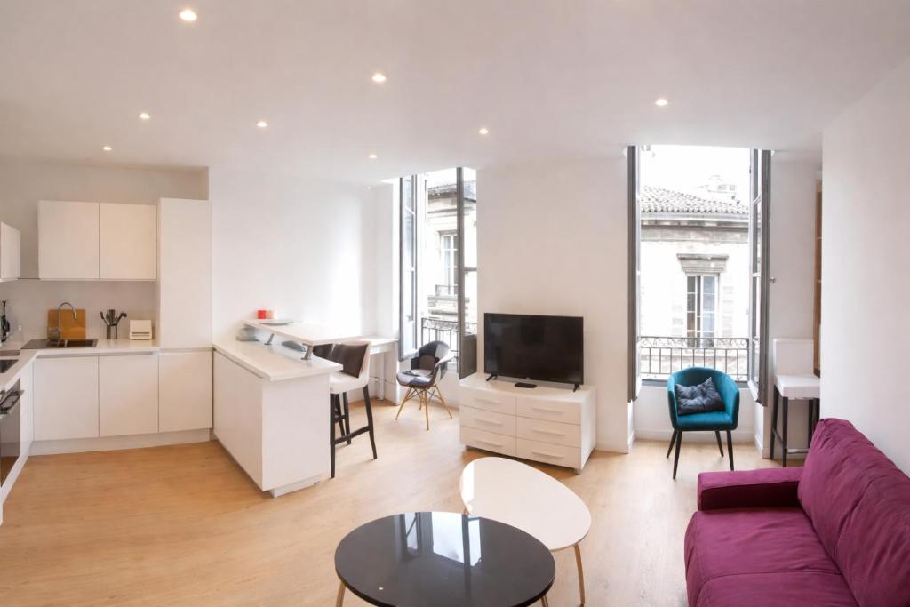 a living room with a purple couch and a kitchen at Logement entier rue Sainte Catherine in Bordeaux