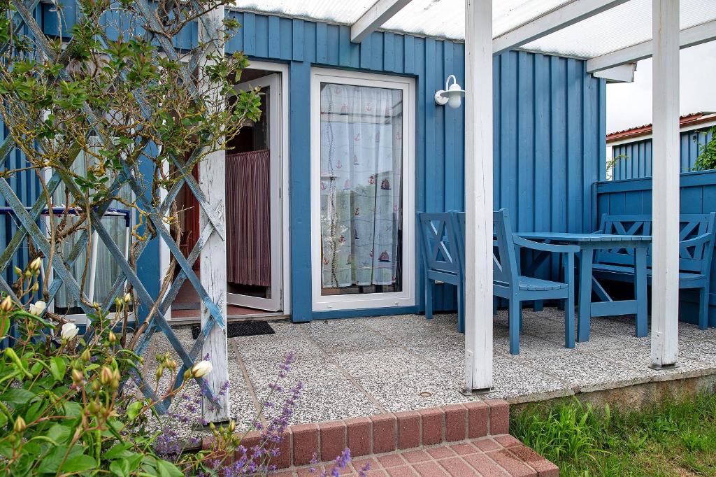 a blue house with a table and chairs on a patio at Möve Aba Bungalow 62 in Rerik