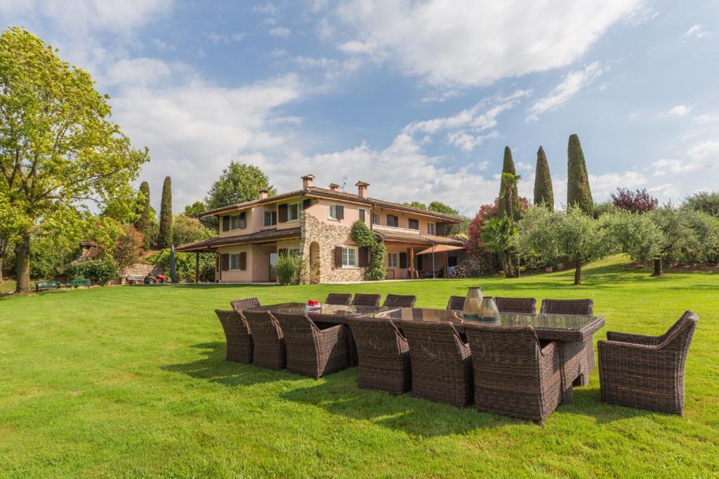 a group of chairs sitting in the grass in front of a house at Villa Minerva in Lazise