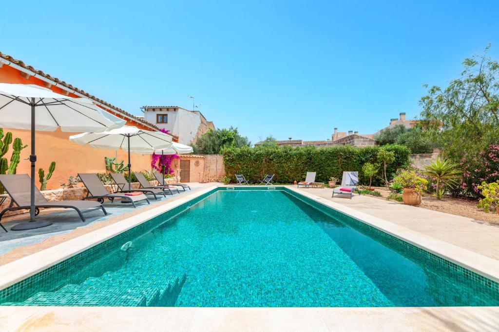 a swimming pool with chairs and an umbrella at El Palomar in Santanyi