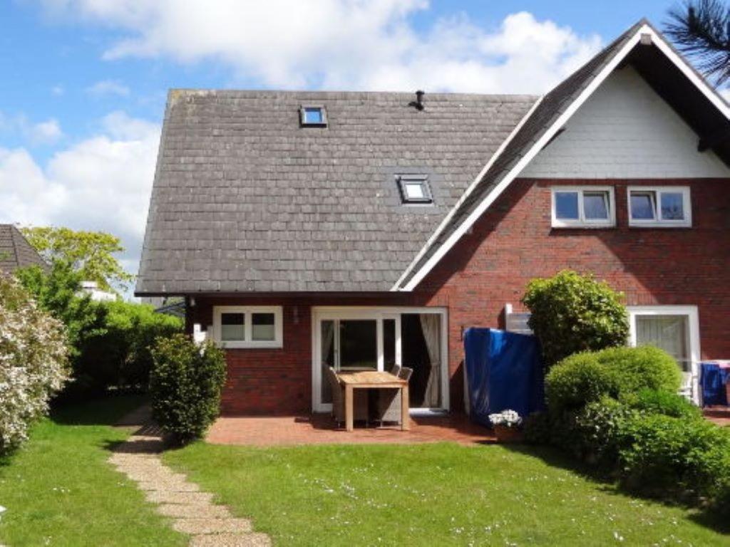 a red brick house with a table in the front yard at Sylthus-Haithabu in Wenningstedt