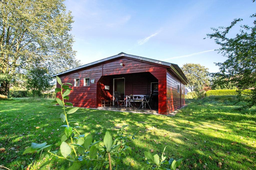 a red barn with a table and chairs in a field at Holzhaus Grimm in Fedderingen