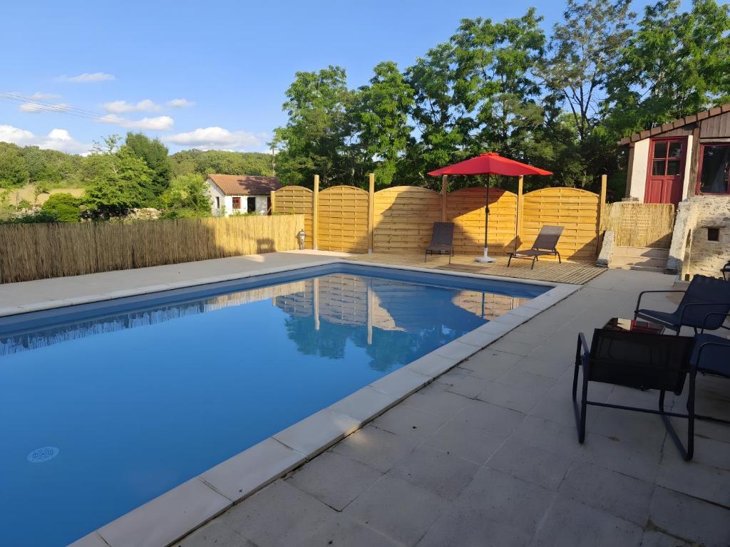 a swimming pool with chairs and a red umbrella at Mas De Palaille, Piscine et Nature in Salvagnac-Cajarc