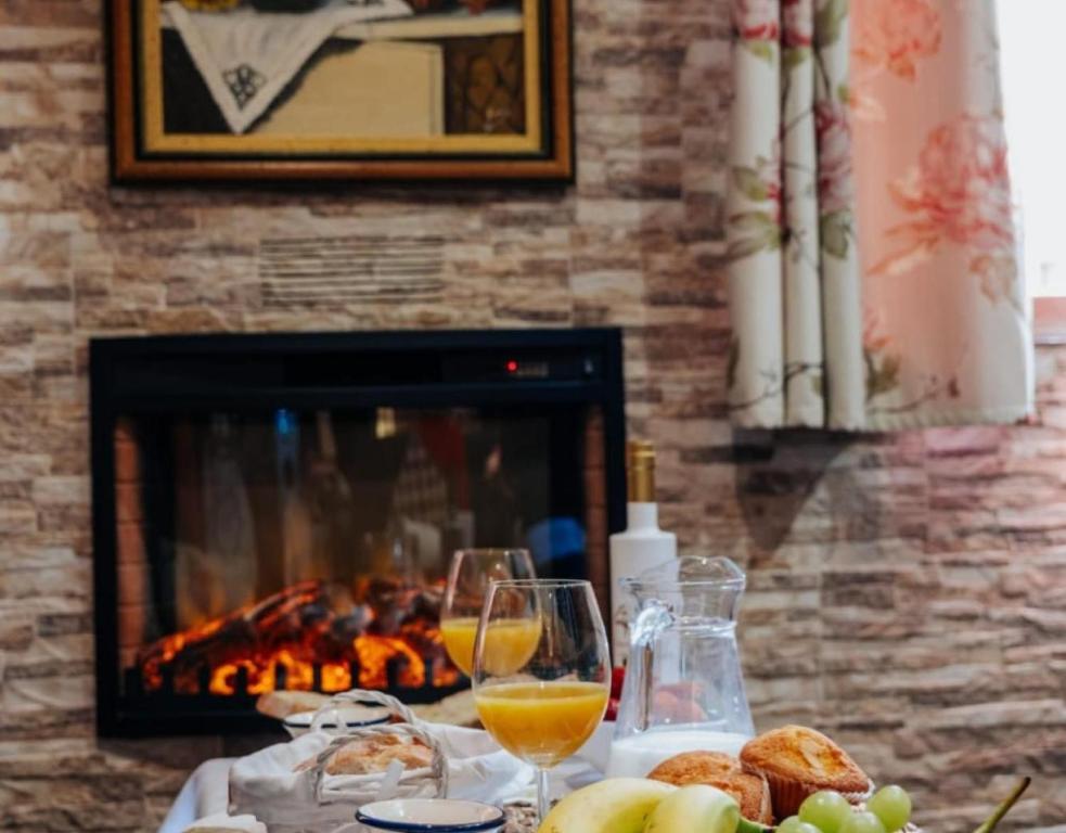 a table with glasses of wine and bread and a fireplace at Casa Rural Los Enebros in Los Navalucillos