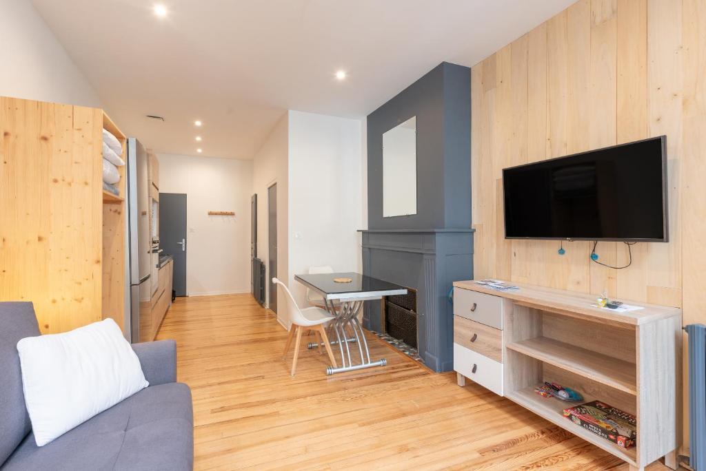 a living room with a couch and a tv on a wall at Studio cosy & design in Bagnères-de-Bigorre
