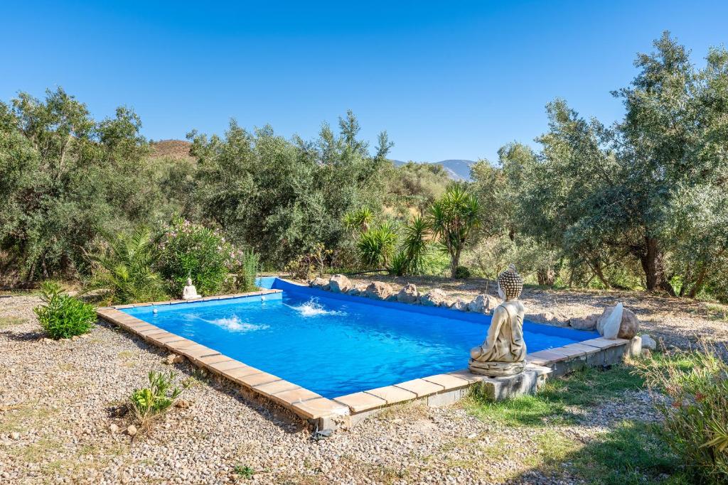 a swimming pool in a garden with a statue next to it at Cabaña Shadú in Lanjarón