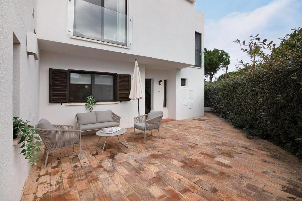 a house with a patio with two chairs and a couch at Pear Tree Villa in Vale do Lobo