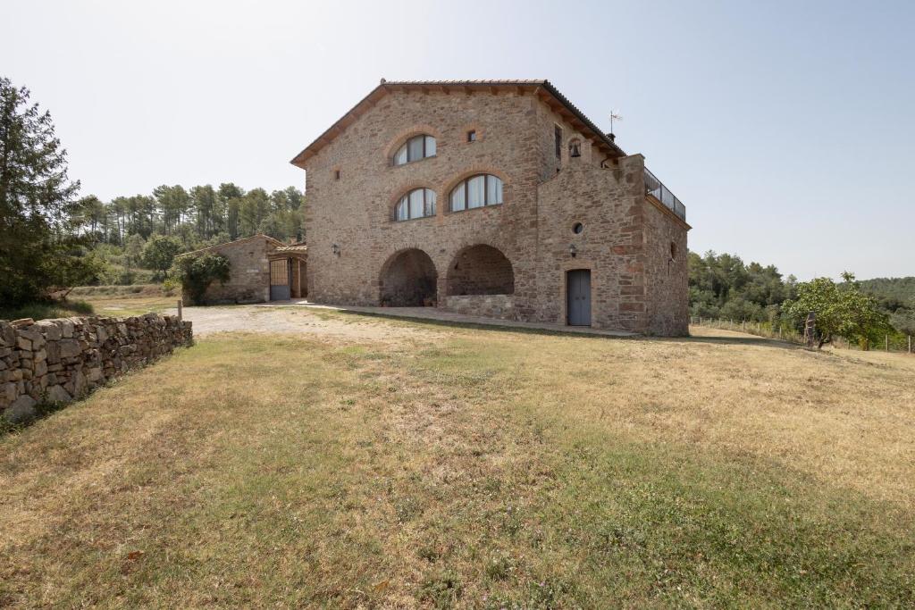 a large brick building in a field next to a stone wall at Torigues in Santa María de Oló