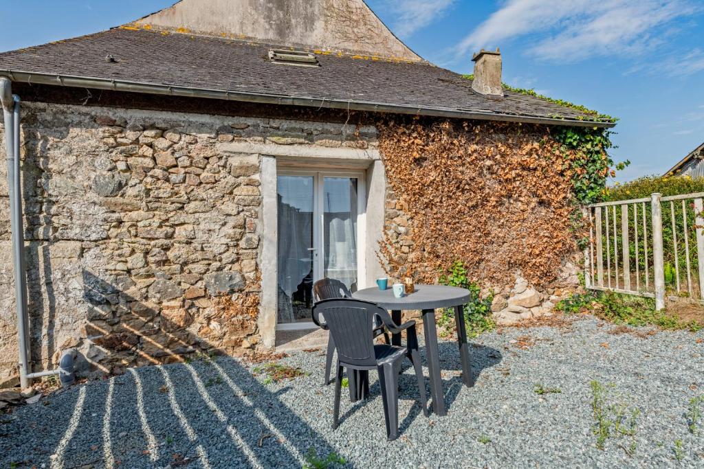a table and chairs in front of a stone building at La Gitounette proche Monts d'arrée in Poullaouen