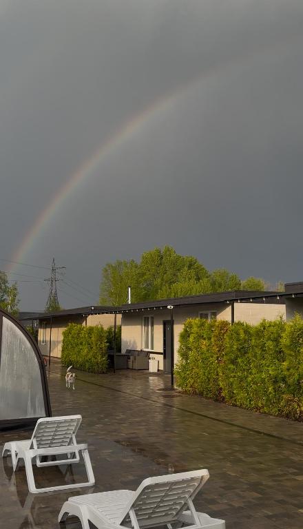 a rainbow over a parking lot with two white benches at Harmony Cottage in Kyiv