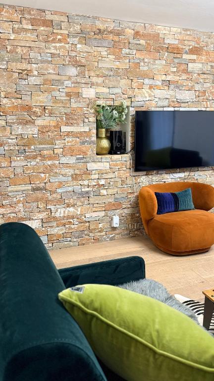 a living room with a brick wall with a flat screen tv at Passage des bains in Annecy