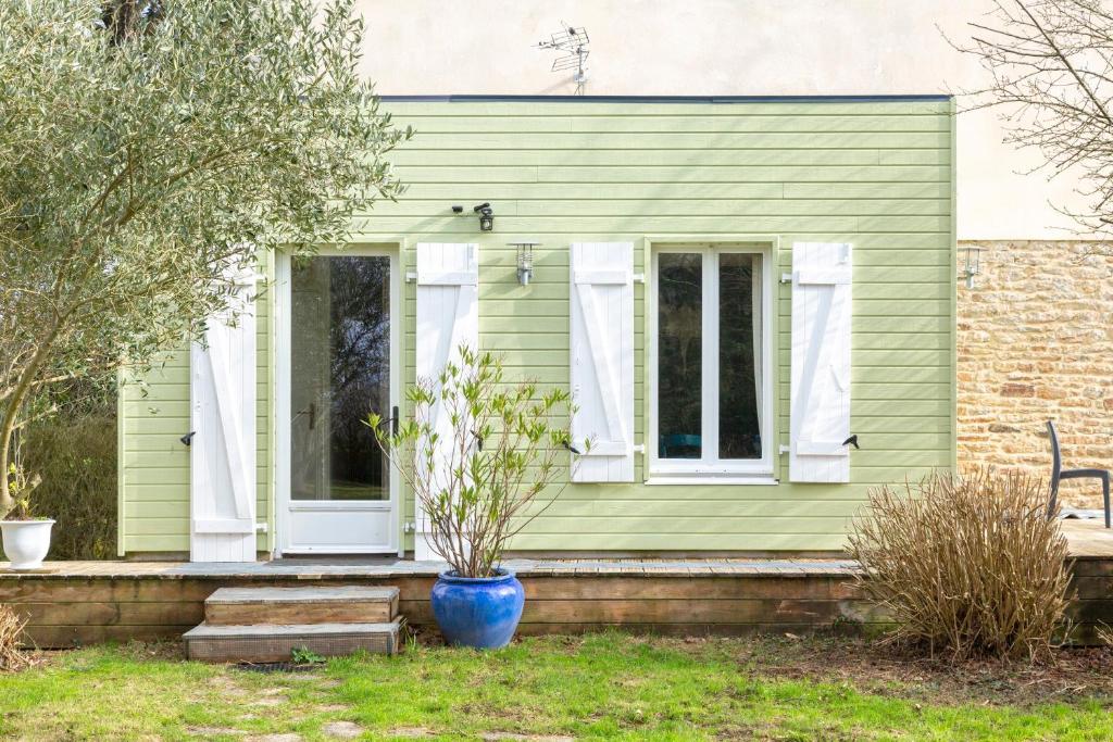 a green house with a blue vase on the front porch at Studio - petit déj inclus in Concarneau
