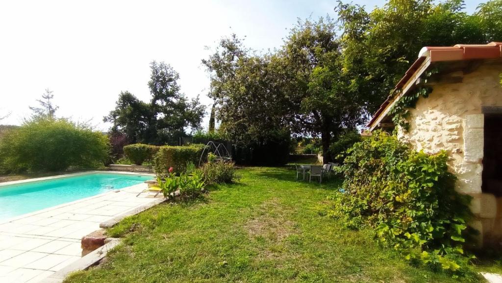 a garden with a swimming pool in front of a house at Chambres d' hotes Terre Happy in Ribérac