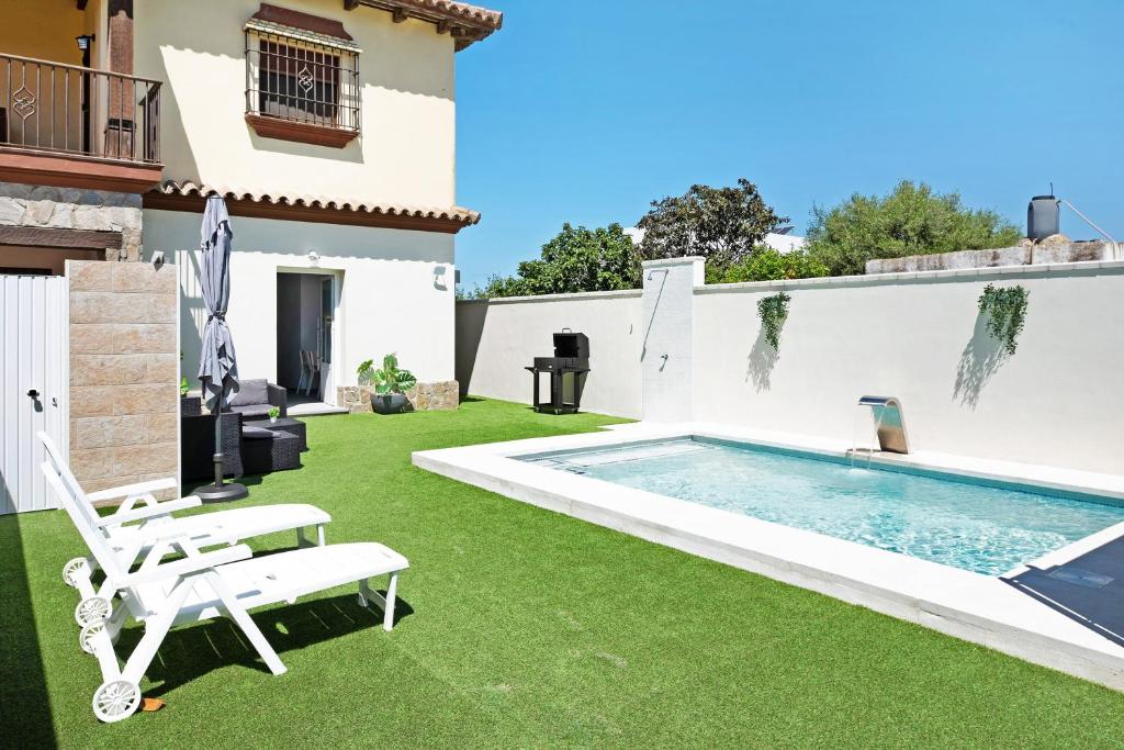 a backyard with a swimming pool and grass at Villa Soleva in Conil de la Frontera