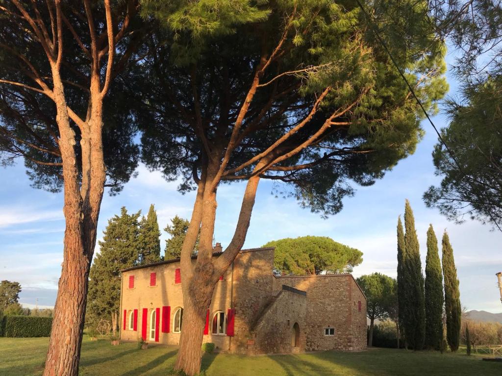 an old stone building with red doors and trees at La Casa Rossa 2 in Bibbona